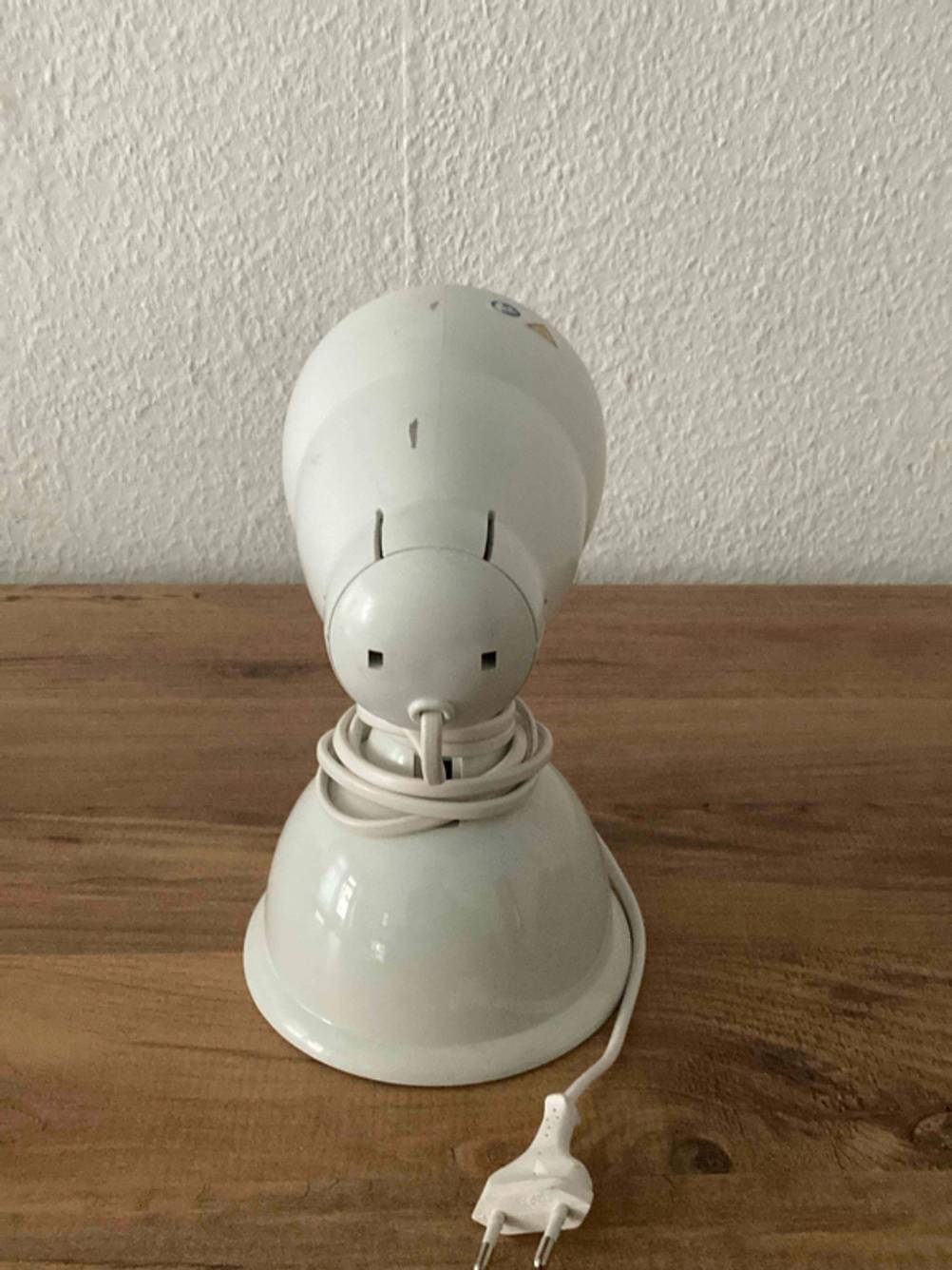 Rückansicht einer getesteten Rotlichtlampe, die vor einer weißen Wand steht.