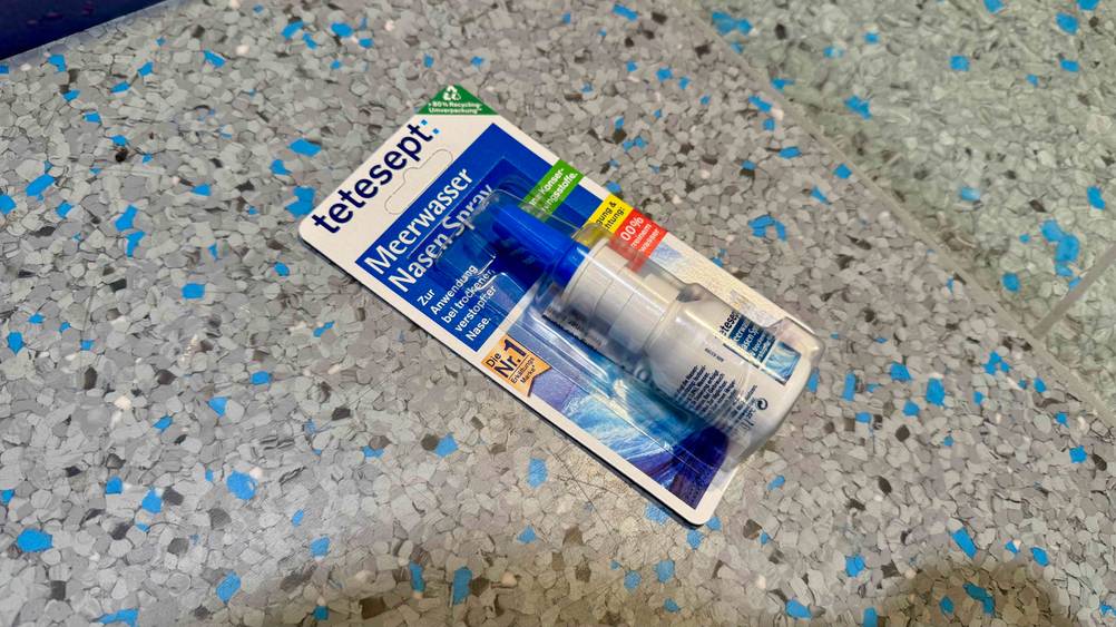 Auf einem grauen Boden liegt ein verpacktes Meerwasser-Nasenspray im Test.
