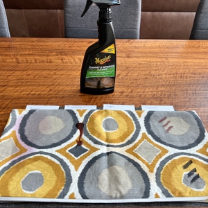 Ein dreckiger Kissenbezug liegt vor dem Meguiar's Polsterreiniger ME G9416 auf einem Tisch