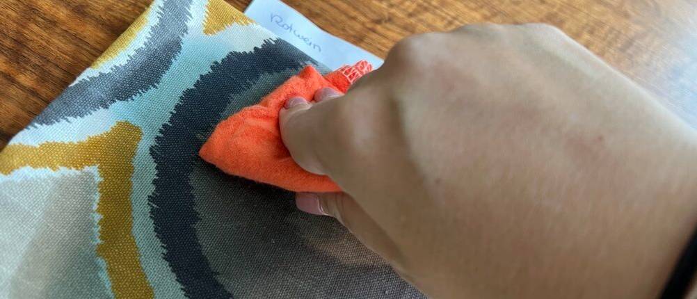 Eine Hand wischt mit einem Lappen über einen Rotweinfleck.