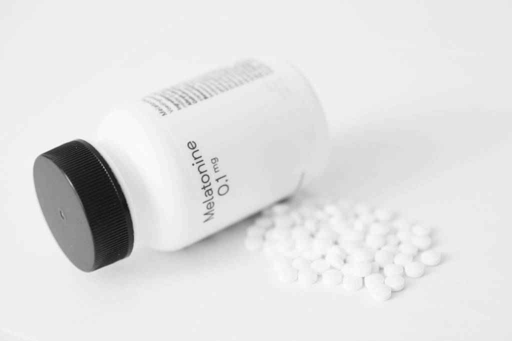Melatonin-Kapseln-Test: Eine Melatonin-Dose liegt neben mehreren Melatonin-Kapseln auf einer hellen Oberfläche. 