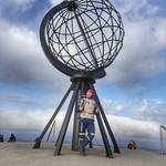 Motorrad-Experte Meli Schönbrodt vor einem Kunstwerk aus Metall in Form eines Globus vor blauem Himmel.