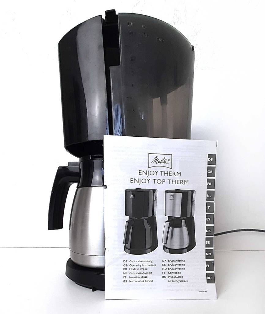 Eine Melitta-Kaffeemaschine steht zum testen mit Bedienungsanleitung auf einer weißen Fläche.