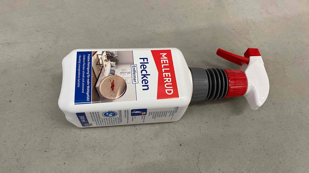 Eine Flasche getesteter Fleckenentferner horizontal auf einem Betonboden.