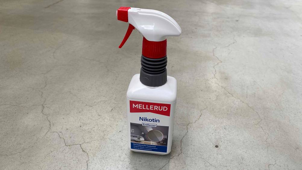 Sprühflasche mit getestetem Mellerud-Nikotinentferner steht auf grauem Boden.