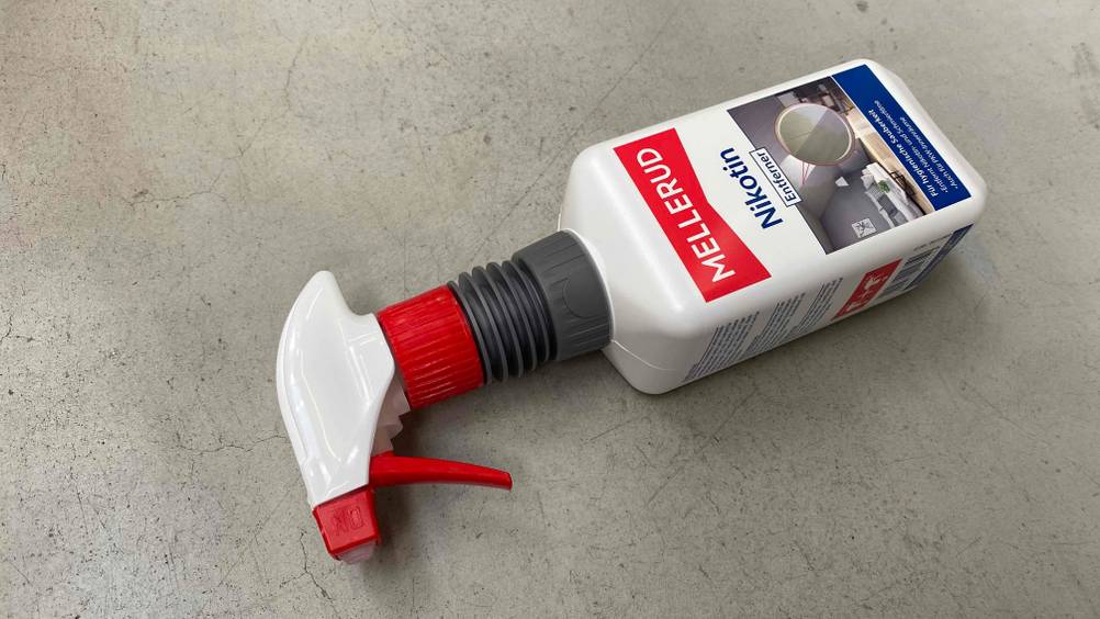 Sprühflasche mit Mellerud-Nikotinentferner im Test liegt auf einem grauen Boden.