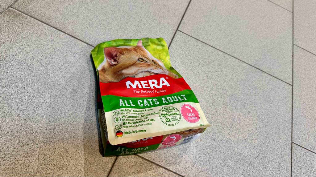 Eine Packung getestetes Mera-Katzenfutter liegt auf einem Fliesenboden.