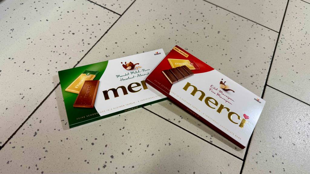Merci-Schokolade im Test: Zwei Tafeln liegen halb übereinander auf einem Fliesenboden.