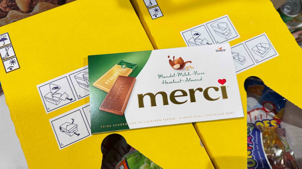 Eine Tafel getestete Merci-Schokolade liegt auf zwei Kartons mit Fruchtgummi.
