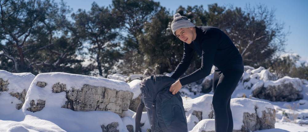 merino-unterwaesche-herren-test: Mann in langer, schwarzer Skiunterwäsche in schneebedeckter Berglandschaft