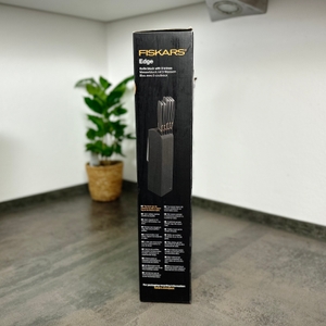 Die linke Seite der Verpackung des Fiskars 6424009787917 zeigt ein Produktfoto mit allen fünf Messern im Block. Die Box steht frei auf dem Boden.