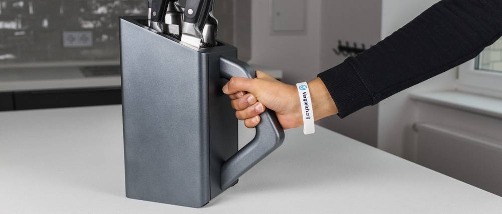 Ein grauer Messerblock wird von einer Hand gegriffen.