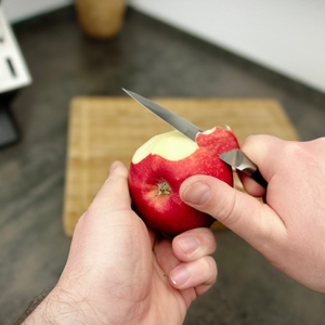 Ein Apfel wird mit einem kleinen Messer aus dem Zwilling-Set geschält. Das Brett steht im Hintergrund bereit.