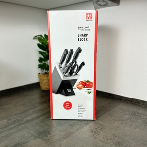 Die Vorderseite der Verpackung des Zwilling-Messerblocks zeigt das Set mit Tomaten und Kräutern als Deko. Der Block ist vollständig bestückt.