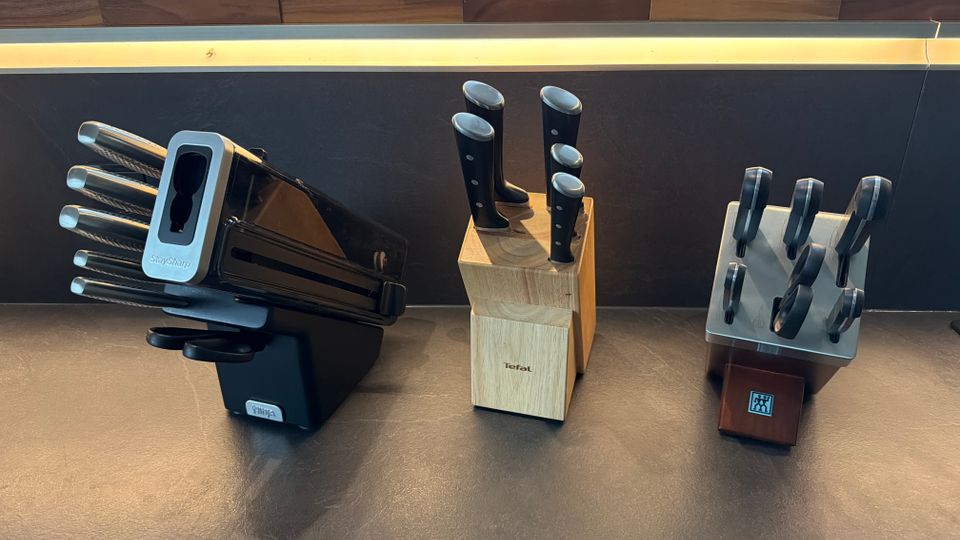 Drei Messersets stehen nebeneinander auf einer Küchenarbeitsplatte.