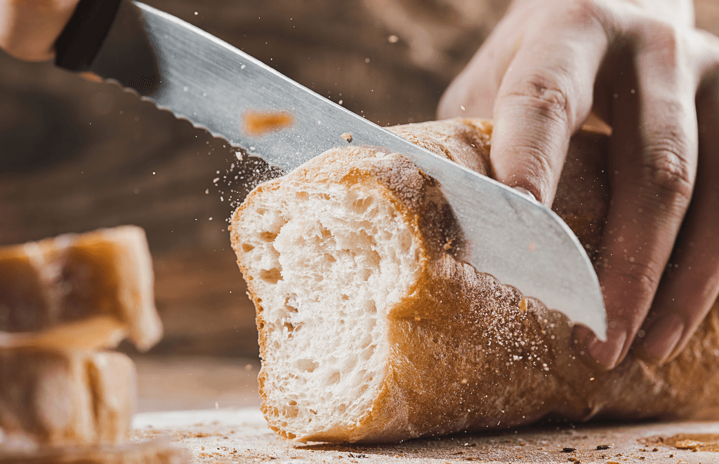 Messerset-Zwilling-Test: Eine Person schneidet Baguette mit einem Brotmesser. 