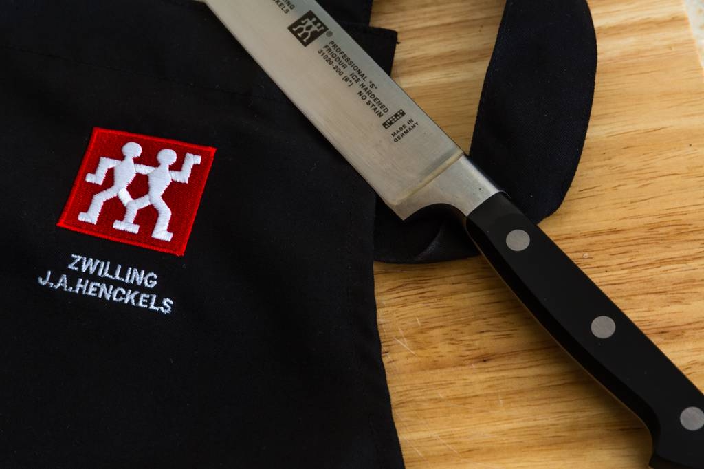 Messerset-Zwilling-Test: Auf einem Brett liegen eine schwarze Tasche von Zwilling und ein Kochmesser von Zwilling. 