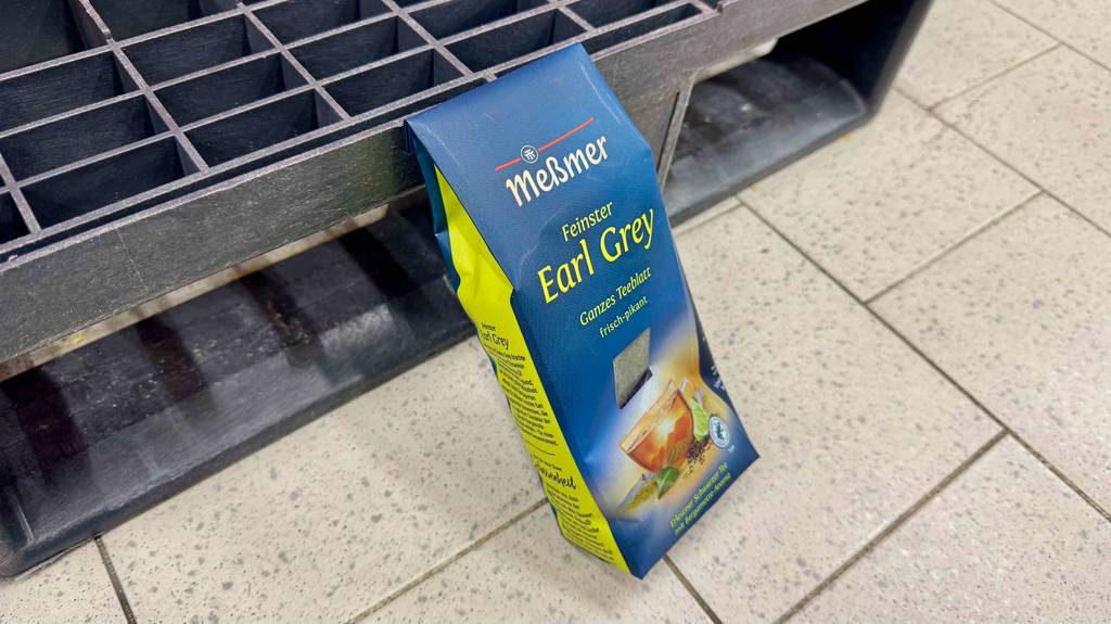 Eine Packung mit getestetem Earl-Grey-Tee der Marke Meßmer steht auf einem Fliesenboden.