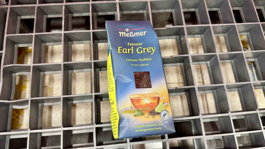 Eine Packung mit getestetem Earl-Grey-Tee von Meßmer liegt auf einem Gitter.