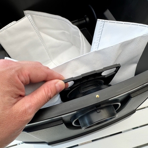 Eine Hand befestigt einen Staubsaugerbeutel am Metabo ASR 25 L SC