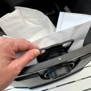 Eine Hand befestigt einen Staubsaugerbeutel am Metabo ASR 25 L SC