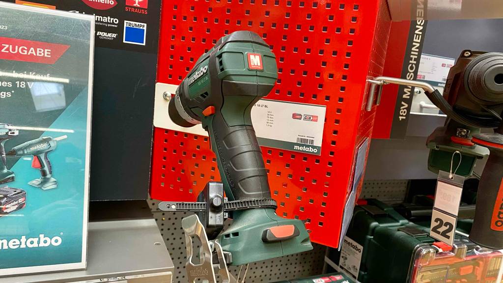 Metabo Akku-Bohrschrauber im Test: Nahaufnahme eines grün-schwarzen Akku-Bohrschraubers von hinten ohne Akku vor einer roten Ausstellungswand in einem Geschäft.
