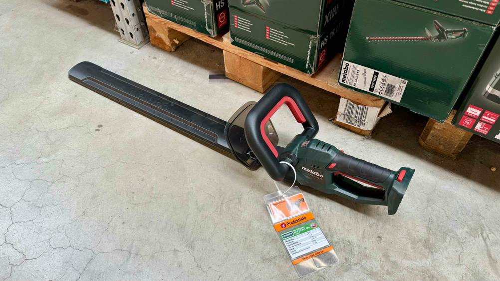 Getestet: Eine Metabo-Heckenschere von schräg oben auf einem Betonboden mit einem Label das Produktinformationen enthält.