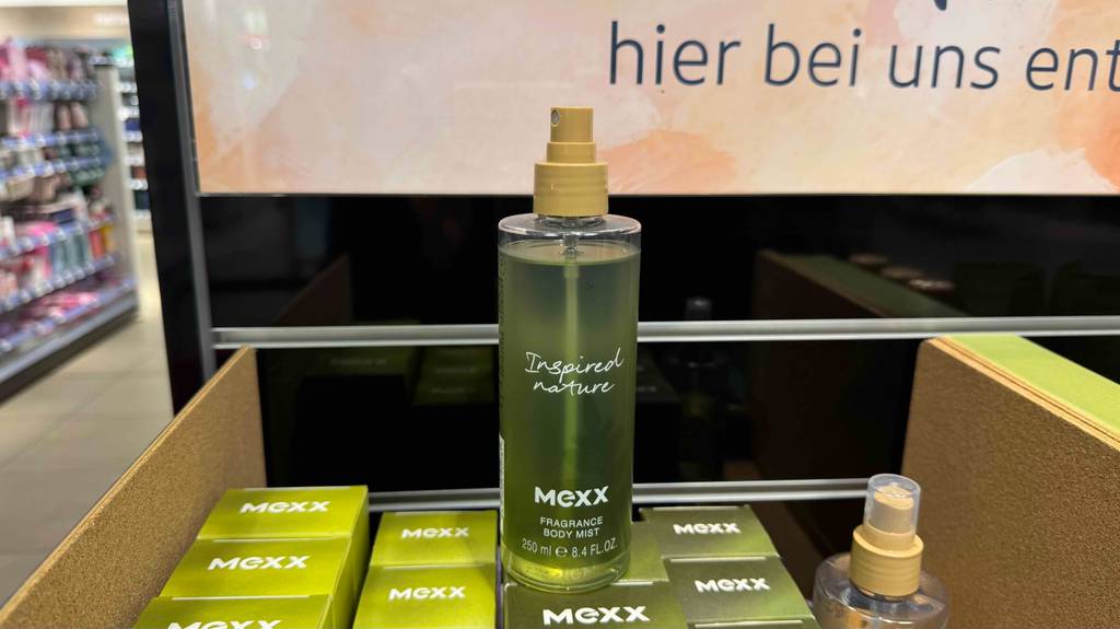 In einer Sprühflasche befindet sich hellgrünes getestetes Körperspray der Marke Mexx, das auf seinen Verpackungen steht.
