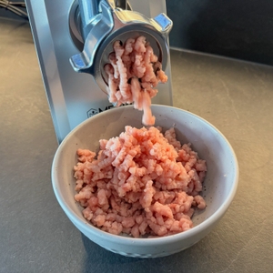 Fleisch kommt aus der Öffnung des Meykey-Fleischwolf