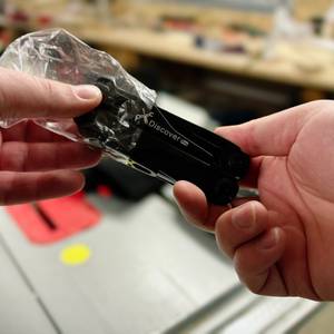Ein schwarzes Miaoke 23-in-1 Multitool wird aus einer transparenten Plastikfolie ausgepackt. Die kompakte Bauweise und der schwarze Griff mit der Aufschrift 