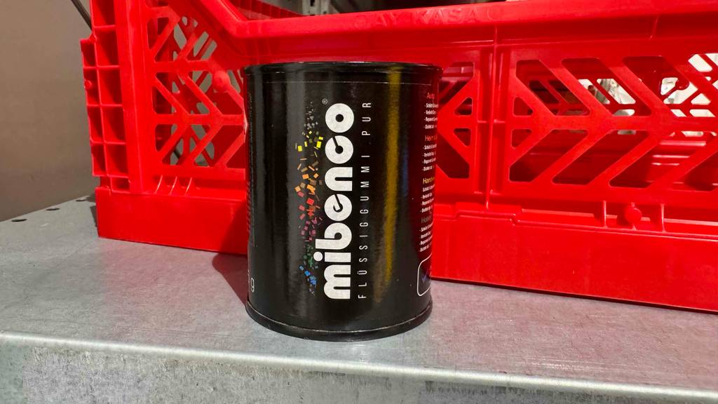 Eine Dose Flüssiggummi steht zum testen vor einer roten Box.