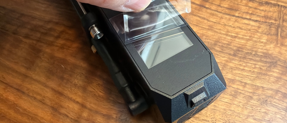 Eine Hand zieht eine Folie vom Display des Michelin-Akku-Mini-Kompressors ab