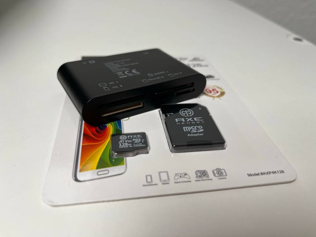 Verpackung mit MicroSD-Karte und passendem Adapter. Darauf liegend ein Kartenlesegerät.