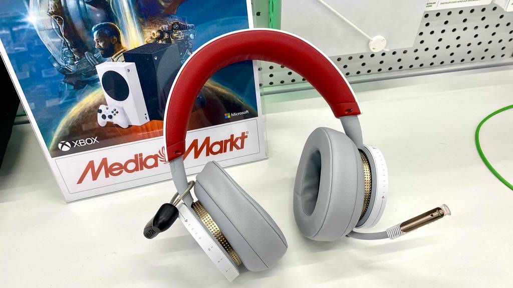 Ein Microsoft Bluetooth-Headset im Test liegt auf einer weißen Ausstellungsfläche im Media-Markt, mit Fokus auf die gepolsterten, hellgrauen Hörmuscheln, dem rot gepolsterten Bügel und dem integrierten Mikrofon.