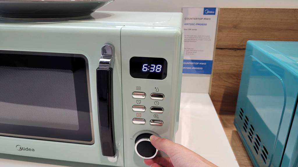 Im Test: Hand dreht am Einstellknopf einer Midea Retro Mikrowelle.