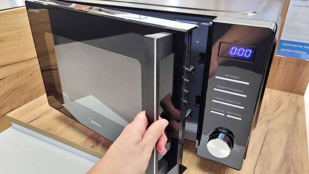 Getestet: Hand öffnet Tür einer Midea Mikrowelle mit 20 Litern.