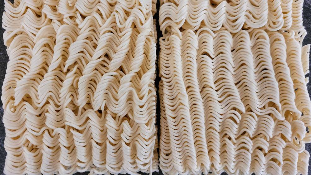 Mie-Nudeln-Test: Nahaufnahme der gepressten Nudel auf einer dunklen Fläche.