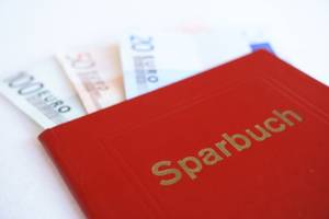 Mietkautionskontos im Test: Ein rotes Sparbuch mit Geldscheinen.
