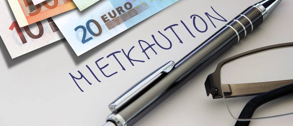 Mietkautionskontos im Test: Mietkaution als geschriebenes Wort, mit einem Stift und Geldscheinen.