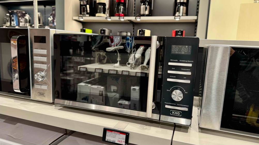 Eine getestete Mikrowelle 23 Liter zwischen anderen Geräten in einem Verkaufsladen.