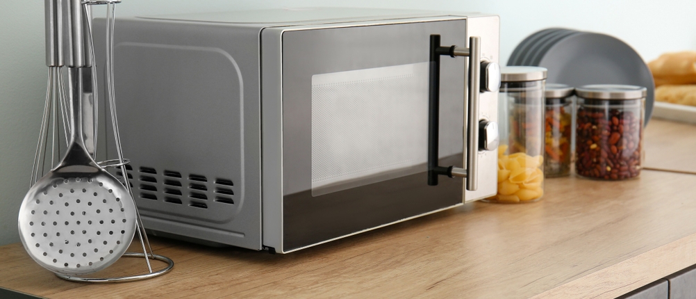 Mikrowelle ohne Drehteller im Test: Eine Mikrowelle steht auf der Küchenzeile. Daneben befinden sich Kochutensilien, Gläser mit Lebensmitteln und Teller.