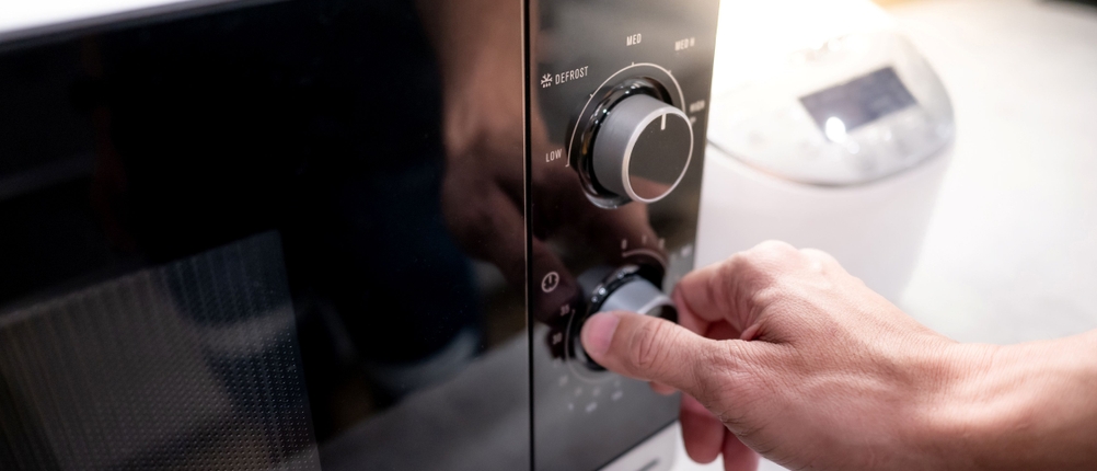 Mikrowelle ohne Drehteller im Test: Eine Person stellt eine Mikrowelle ein.