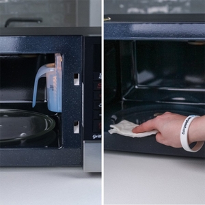 Person reinigt Mikrowelle von innen.