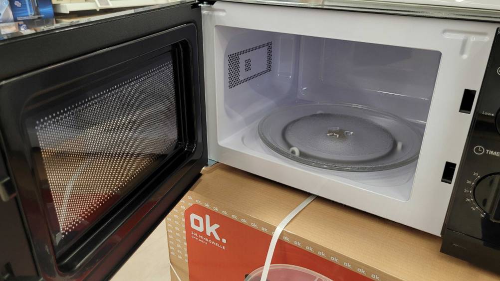 Eine geöffnete Mikrowelle unter 100 Euro im Test auf einem Karton.