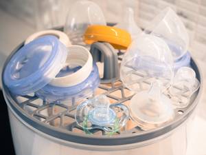 Mikrowellen-Sterilisator-Test: Auf einem Einlagegitter des Mikrowellen-Sterilisators liegen Babyflaschen-Teile und ein Schnuller. 