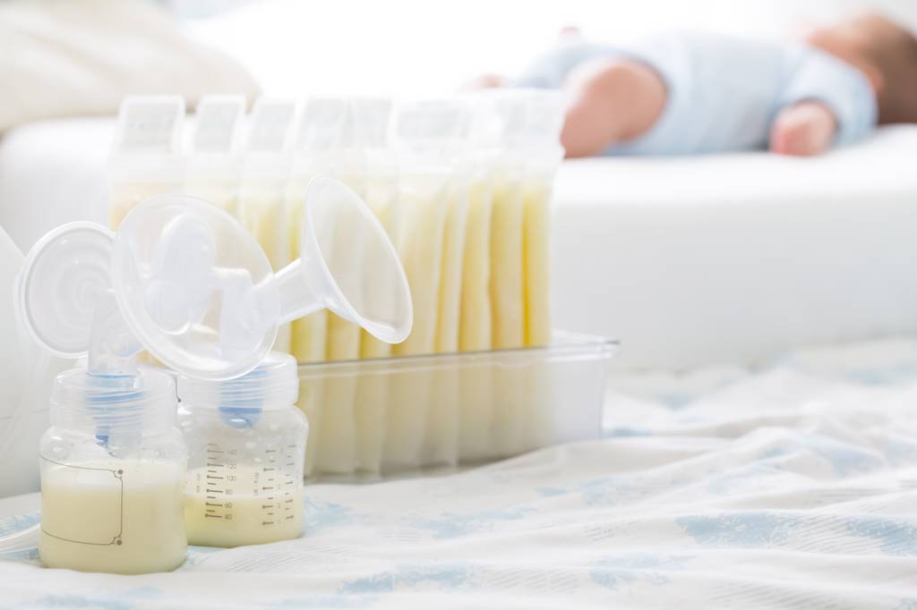 Mikrowellen-Sterilisator-Test: zwei manuelle Milchpumpen stehen neben mehreren Beuteln mit Muttermilch auf einem hellen Leintuch. 