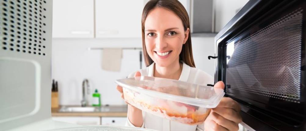 Mikrowellendose-Test: Frau hält Mikrowellendose mit Essen in der Hand.