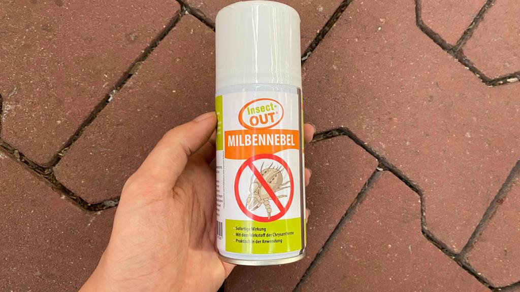 In der Hand befindet sich ein getestetes Milbenspray. 