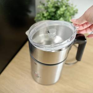 Eine Hand greift den transparenten Deckel des WMF Lono Milk & Choc Milchaufschäumers. Der Deckel ist leicht gewölbt und durchsichtig.