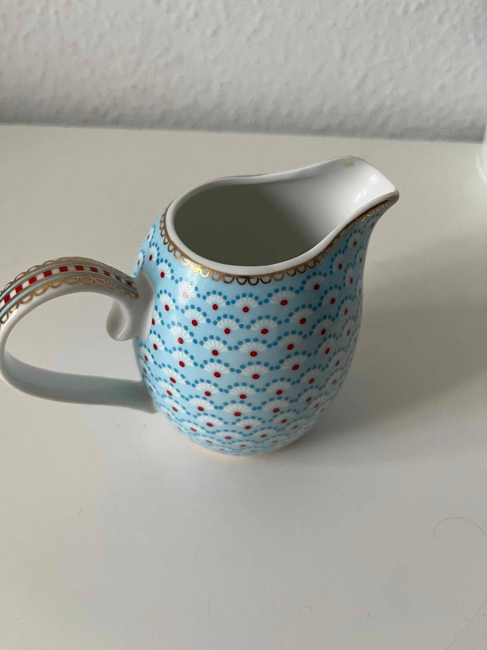 Ein getestetes Milchkännchen mit Muster von schräg oben auf einer hellen Fläche.